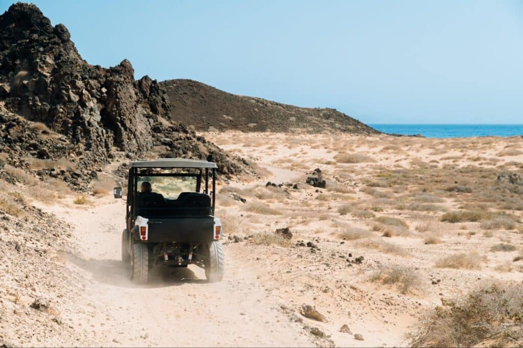 Visitor driving a golf cart along a sandy beach road on Anna Maria Island.